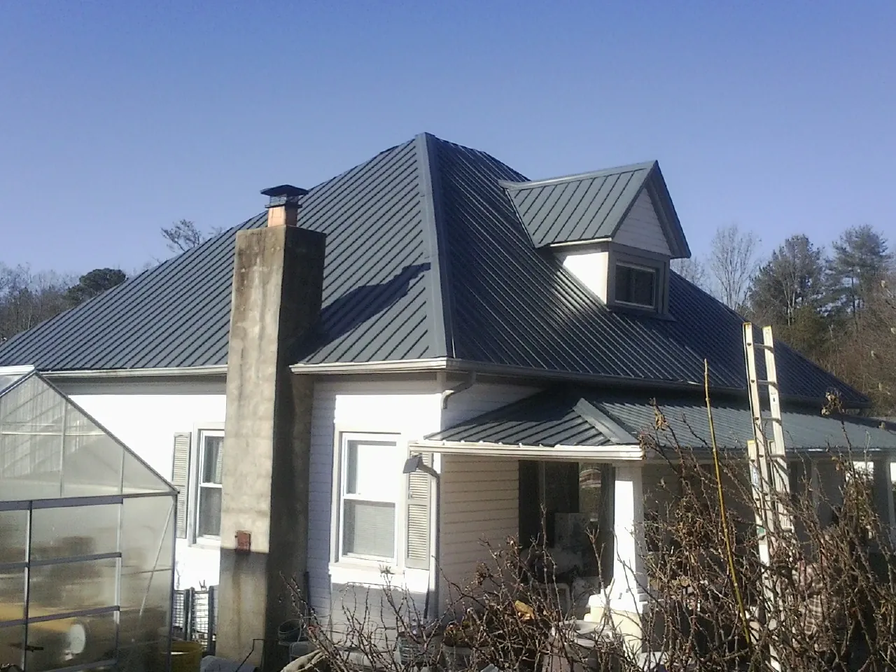 Dark blue standing seam metal roof on a white farmhouse with dormer — Slate & Tile Roof Repair by Roofing Brothers in Twin Bridges