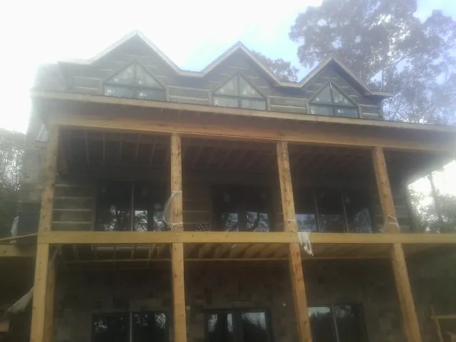 Dormers and porch framing on a large log home under construction — Roof Coating work by our crew in Twin Bridges