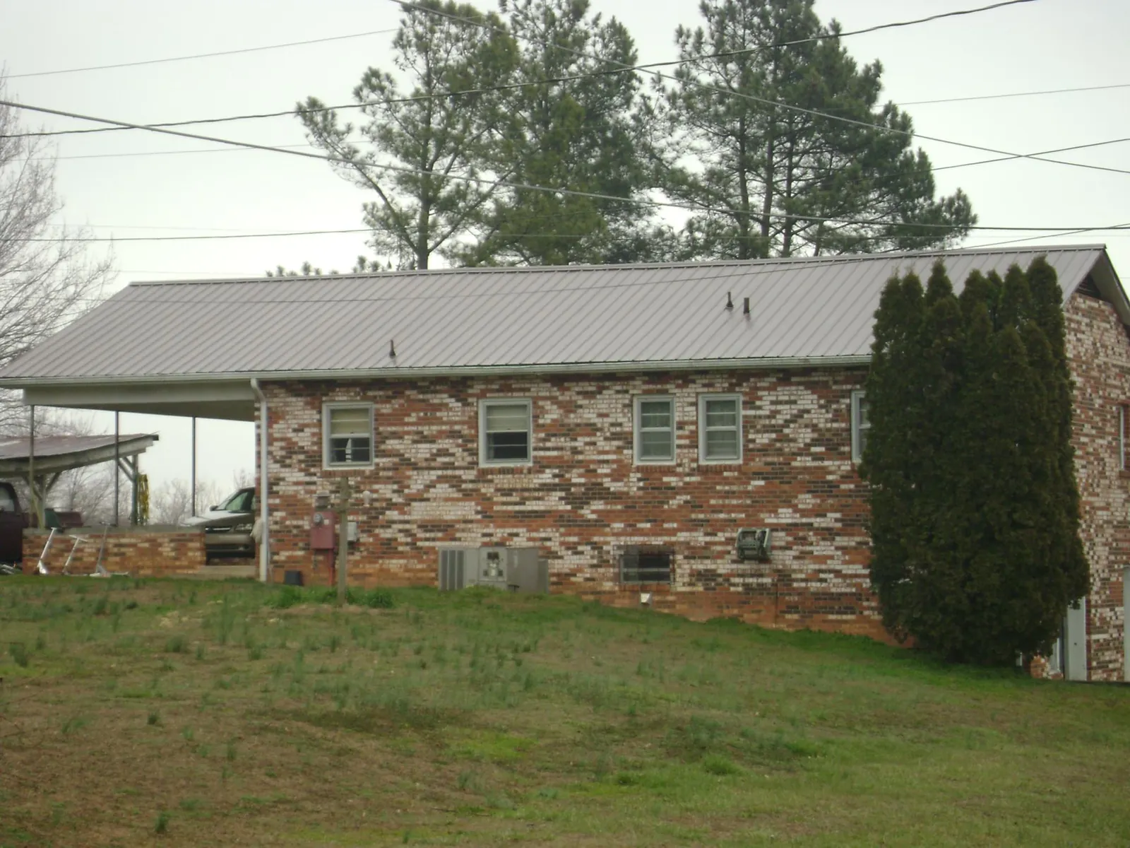 Gray metal roof on a brick split level home with a carport in Twin Bridges