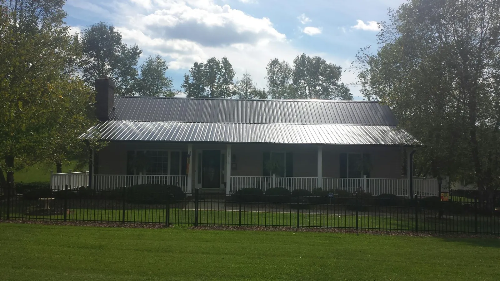 Gray metal roof on a brick ranch with a full width front porch — Gutter Guard Installation work by our crew in Twin Bridges