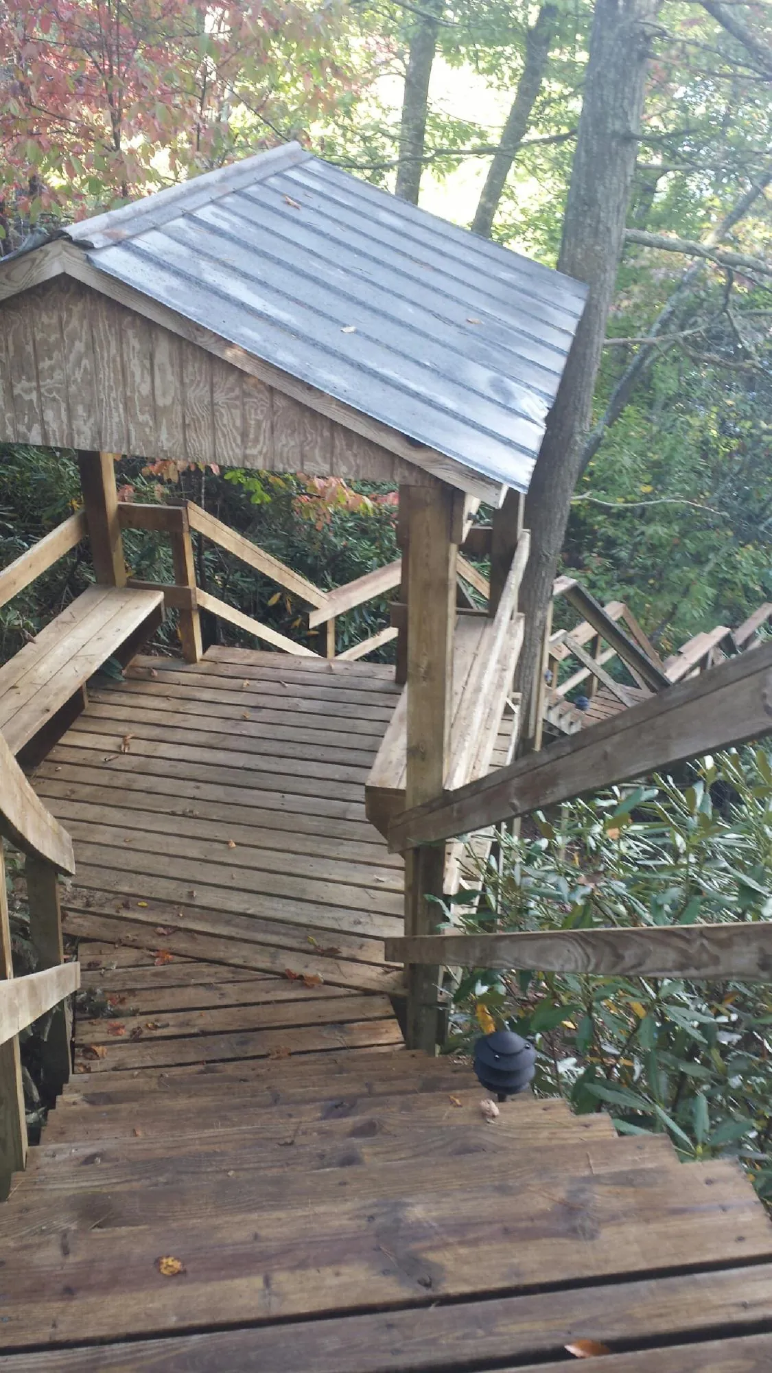 Metal roofed shelter over wooden steps on a wooded walkway — Skylight Repair & Installation work by our crew in Twin Bridges