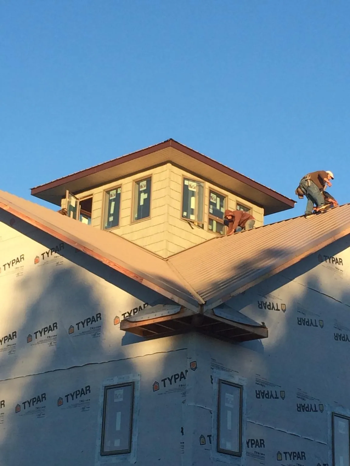 Roofers working around a rooftop cupola on a new metal roof at sunset — Roof Waterproofing in Twin Bridges by Roofing Brothers